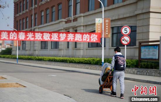 高三年级返校学生从“最美的春光致敬逐梦奔跑的你”条幅下走过。　陈良臻